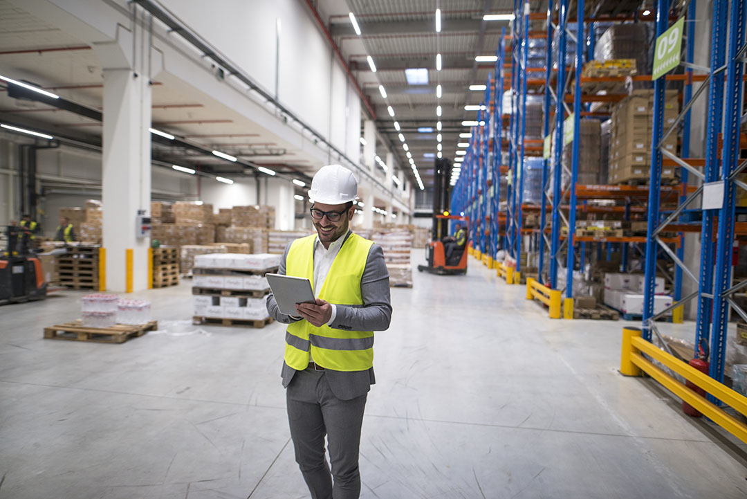 Warehouse manager walking through large storage area and holding